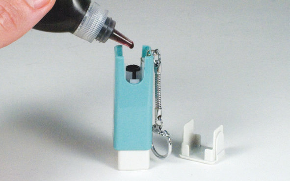 Removing the white cap from a keychain Xstamper stamp and adding refill ink to the centre opening