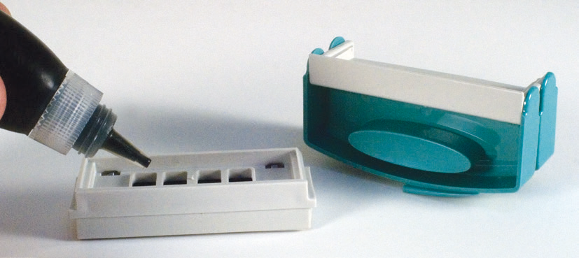 Placing drops of refill ink into the openings of the pocket stamp's impression cartridge