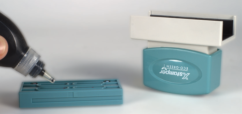 Placing drops of refill ink into the four openings of the rectangular stamp's impression cartridge