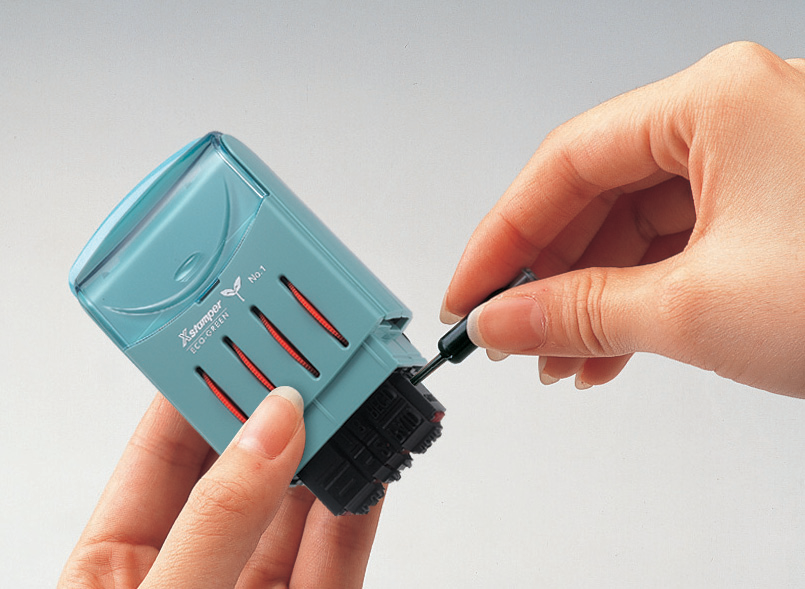 Placing drops of Xstamper ink into the re-inking hole of the VersaDater