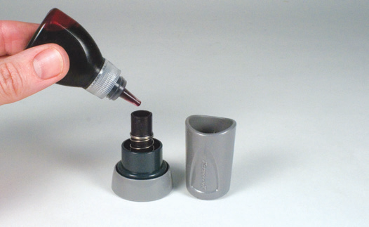Xstamper vX message stamp handle separated from the mount, showing the inking openings